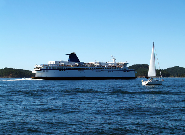 Gran ferry y velero en marcha en la bahía
 - Foto, Imagen