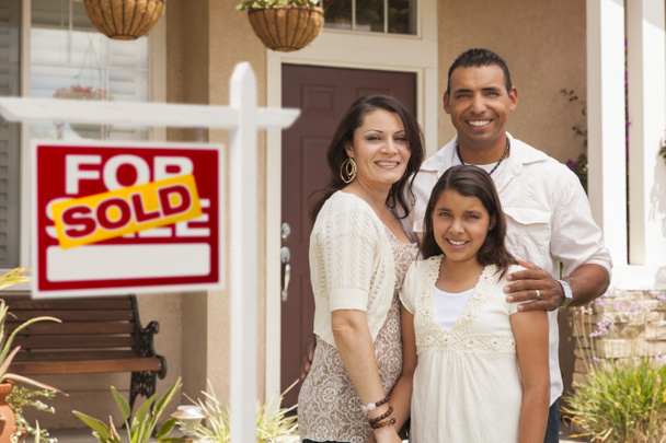 Família hispânica na frente de sua nova casa com sinal de venda
 - Foto, Imagem