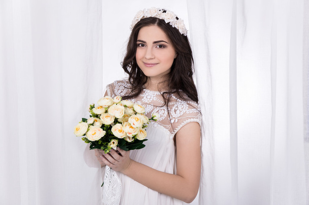 mooie bruid in witte jurk met bloemen - Foto, afbeelding