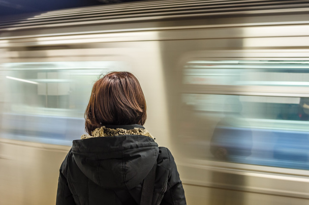 Train Pulling into the Platform in Front of Woman Waiting for it - 写真・画像