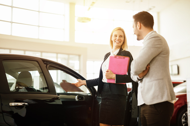 Salesperson showing vehicle to potential customer - 写真・画像