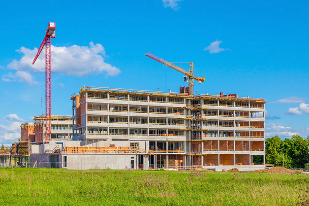 budynek i żurawie w budowie przeciw błękitne niebo - Zdjęcie, obraz