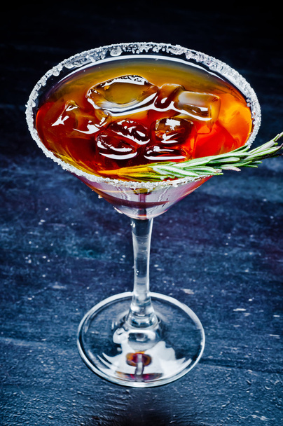 sweet alcoholic cocktail with ice and a sprig of rosemary - Foto, afbeelding