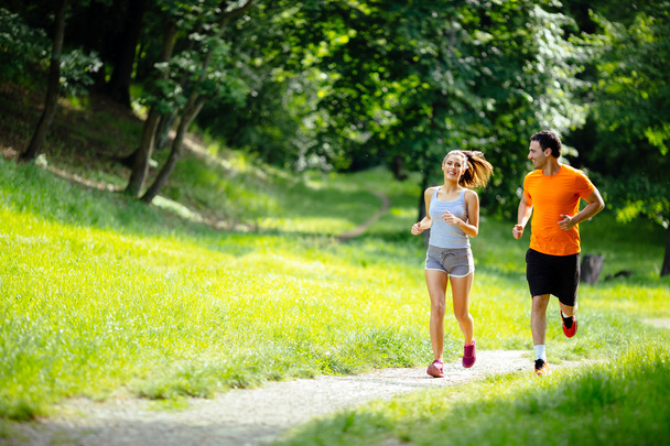 Athletic couple jogging in nature - Фото, зображення
