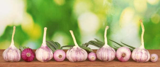 Young garlic and onion on wooden table on bright green background close-up - Zdjęcie, obraz