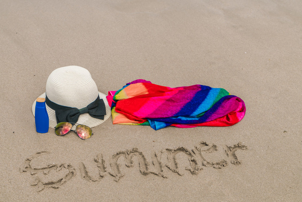 Sunglasses, sun cream and hat  on white  sand beach - Photo, Image