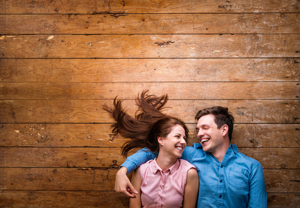 Beautiful young couple hugging against wooden background - Foto, imagen