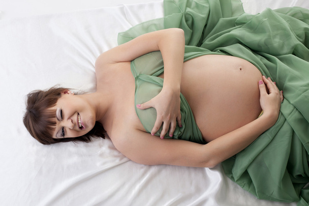 Happy pregnant woman lying in bed - Foto, afbeelding