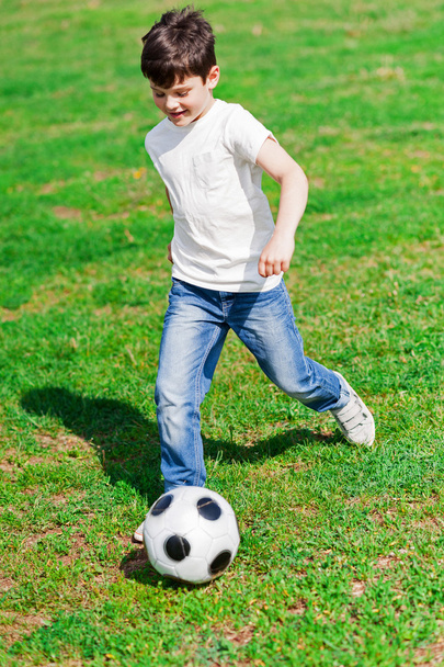 Muito masculino criança jogando futebol na grama
 - Foto, Imagem
