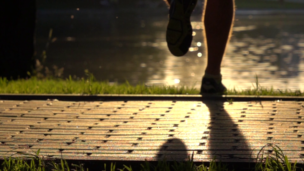 Super-Zeitlupe-Clip von Sommer-Sonnenuntergang Park und Läufer läuft vor Kamera weg - Filmmaterial, Video