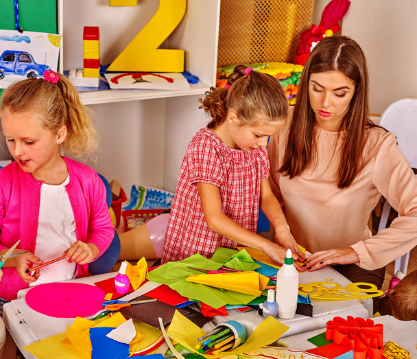 Niños sosteniendo papel de color en la mesa en el jardín de infantes
 . - Foto, Imagen
