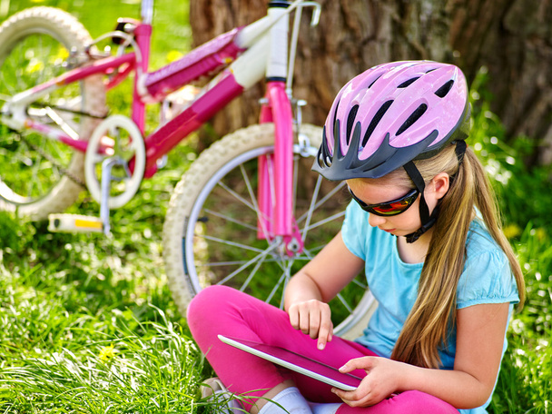 Kerékpárok kerékpáros lány visel sisakot nézi tábla PC . - Fotó, kép