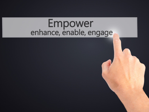 Empower enhance, enable, engage - Hand pressing a button on blur - Photo, Image