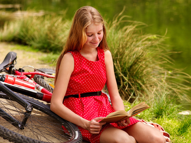 Bikes cycling girl into park read book bicycle on shore. - Photo, Image