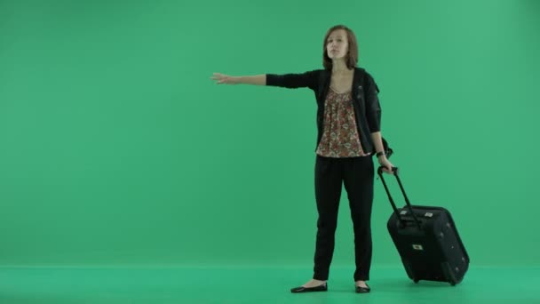 woman with suitcase thumbing a ride - Materiał filmowy, wideo