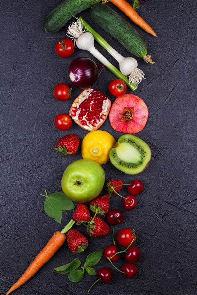 Möhren, Rote Bete, Gurken, Zitrone, Granatapfel, Kiwi, Äpfel, Tomaten, Kirschen, Erdbeeren, rote Zwiebeln, Basilikum und Minze. Blick von oben, Top-Studioaufnahme von Gemüse und Obst - Foto, Bild