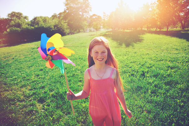 Happy redhead girl with pinwheel toy in park. Freedom, summer, c - Photo, image