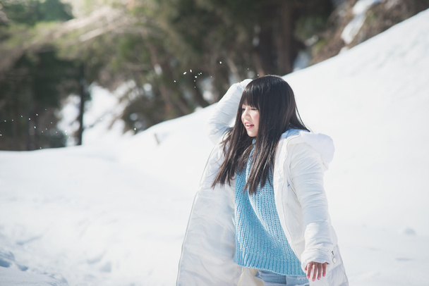Азиатская девушка улыбается на улице в снегу в холодный зимний день
 - Фото, изображение
