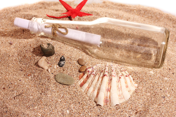 Bottiglia di vetro con nota sulla spiaggia di sabbia con conchiglie
 - Foto, immagini