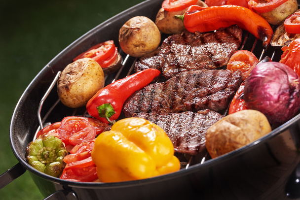 Erilaisia herkullisia grillattuja lihapihvejä, joissa on erilaisia vihanneksia, paprikaa, tomaattia, pippuria, perunaa, hiilien päällä pyöreällä modernilla mustalla grillillä lähikuva viikonloppu tai loma-käsite
 - Valokuva, kuva