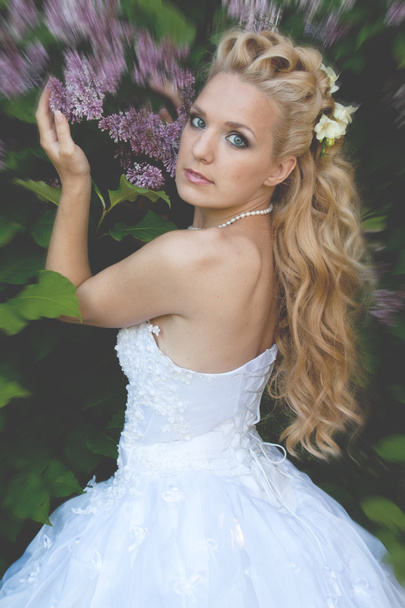 Beautiful girl in a wedding dress with lilac - Photo, Image