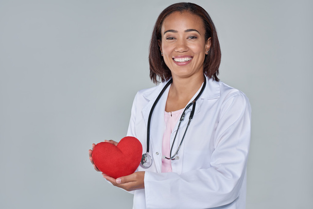 smiling female doctor holding red heart - Foto, imagen