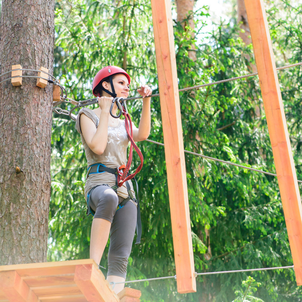 Young woman climbing in adventure park - 写真・画像