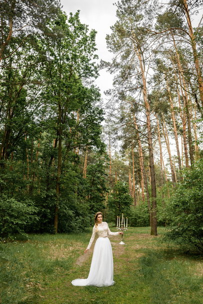 Tyttö kaunis valkoinen mekko kukkakimppu metsässä
 - Valokuva, kuva