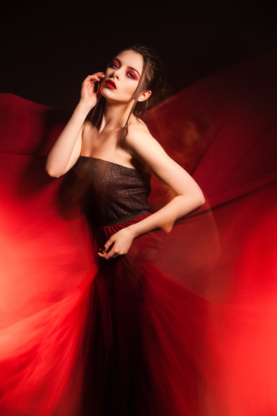 Όμορφη νεαρή γυναίκα σε κουνώντας το κόκκινο φόρεμα - Φωτογραφία, εικόνα
