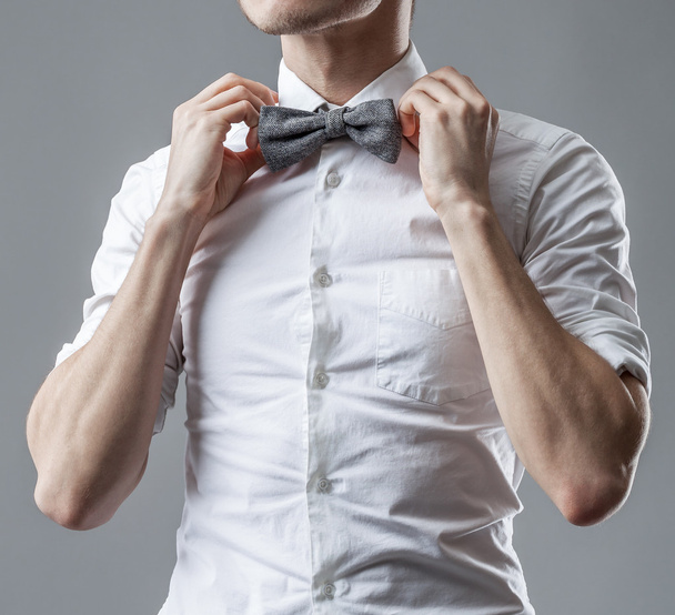 Stylish man in a white classic shirt correcting his bow tie. The official style of clothes. - Foto, imagen