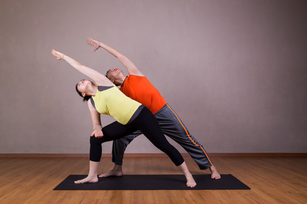 Pár provést sérii rozšířené boční úhel jóga partner představují - Fotografie, Obrázek