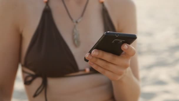 smartphone woman sms texting using app on smart phone on the beach - Metraje, vídeo