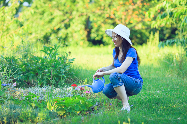 Happy mature woman taking care of her flowers in garden. - Photo, Image