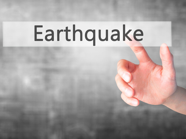 Aardbeving - Hand indrukken van een knop op de onscherpe achtergrond concep - Foto, afbeelding