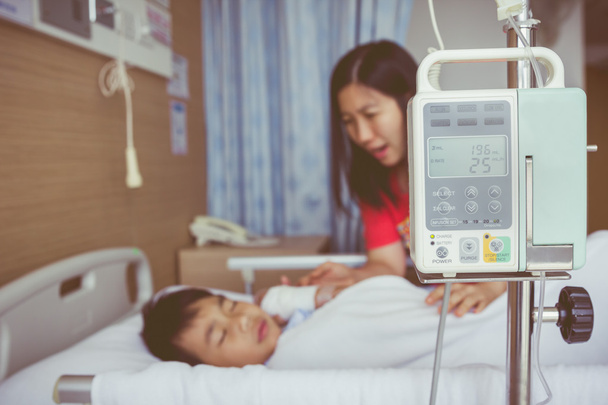 Азиатский мальчик лежит на больничном с инфузионным насосом внутривенной капельницы. Винтажный стиль
. - Фото, изображение