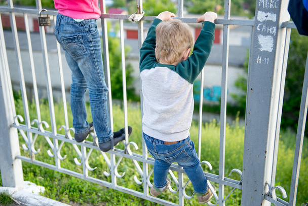 μικρό αγόρι σκαρφάλωσε στο φράκτη - Φωτογραφία, εικόνα