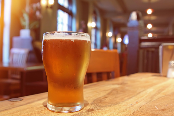 Nahaufnahme eines Glases frisches schäumendes Bier auf einem Tisch in einem Vintage-Unschärfe und Lärm - Foto, Bild