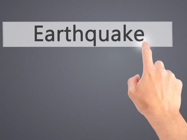 Erdbeben - Hand auf Knopfdruck auf verschwommenem Hintergrund - Foto, Bild