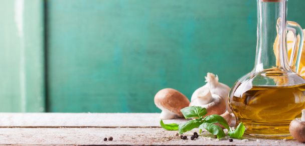 Food background with olive oil, fresh basil, pasta tagliatelle, mushrooms and pepper on a wooden background - Foto, afbeelding