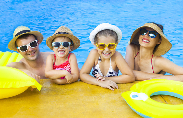 Счастливая семья с двумя детьми развлекается в бассейне
 - Фото, изображение