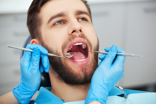 Young man getting his teeth checked by a dentist. - Fotó, kép