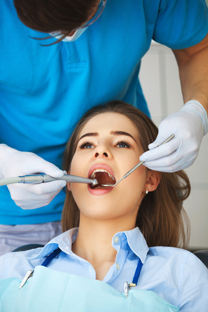 Young woman getting her teeth checked by a dentist. - Foto, afbeelding