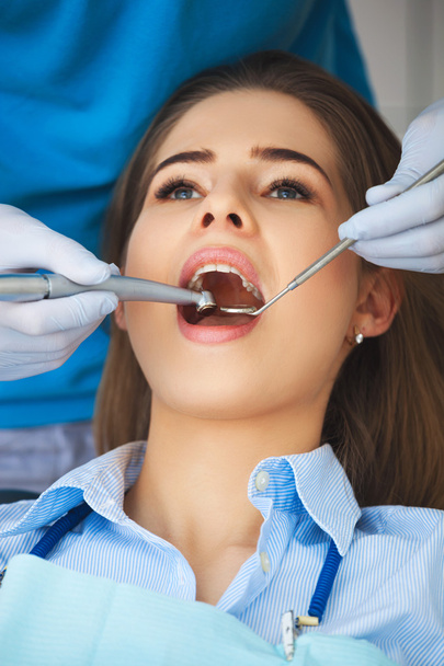 Young woman getting her teeth checked by a dentist. - Фото, зображення