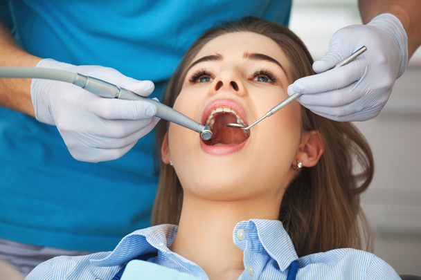 Young woman getting her teeth checked by a dentist. - Фото, изображение