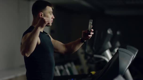 man makes selfie while walking on a treadmill - Materiał filmowy, wideo