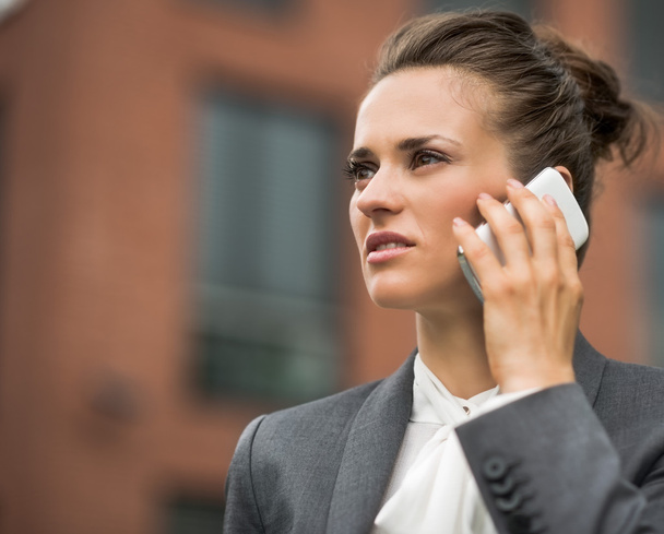 Modern business woman against office building talking smartphone - Photo, Image