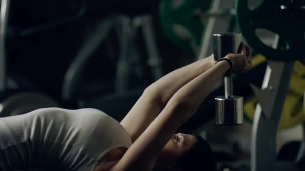 Kadının bir spor salonunda bir bankta bir Dumbbell kazak egzersiz yapması. - Video, Çekim