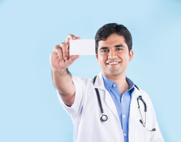 Portrait rapproché d'un professionnel de santé indien confiant ou d'un médecin ou infirmier avec stéthoscope, tenant la carte de visite, espace de copie, médecin indien avec carte blanche, isolé sur fond bleu
 - Photo, image
