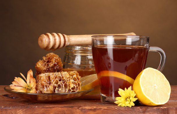 Honey, lemon, honeycomb and a cup of tea on wooden table on brown background - Fotografie, Obrázek