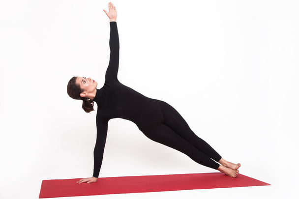 Beautiful athletic girl in a black suit doing yoga. vasishthasana asana sage pose. Isolated on white background. - Foto, immagini